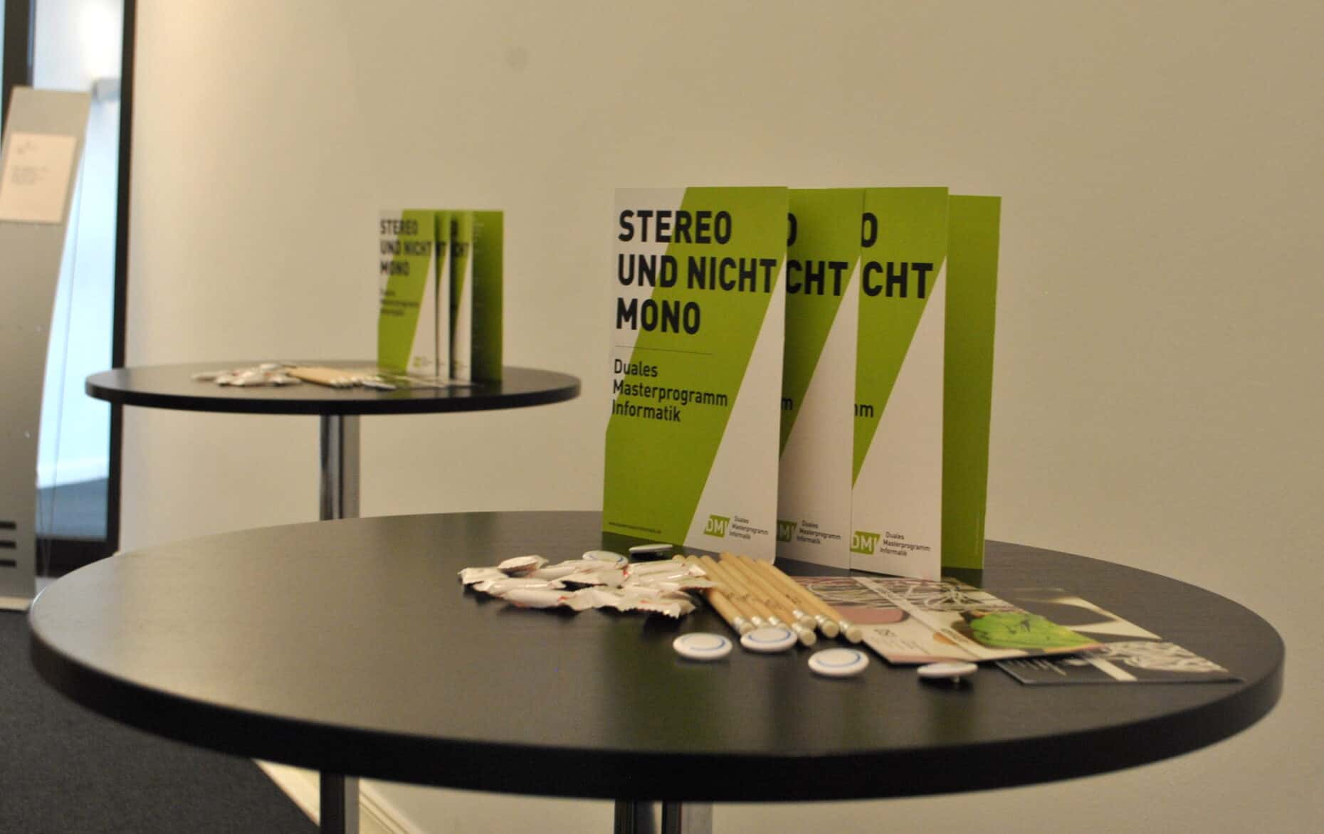 Auf einem runden Tisch stehen Flyer mit dem Titel: Stereo und nicht Mono.