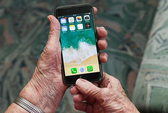 Hände einer älteren Person halten ein Smartphone