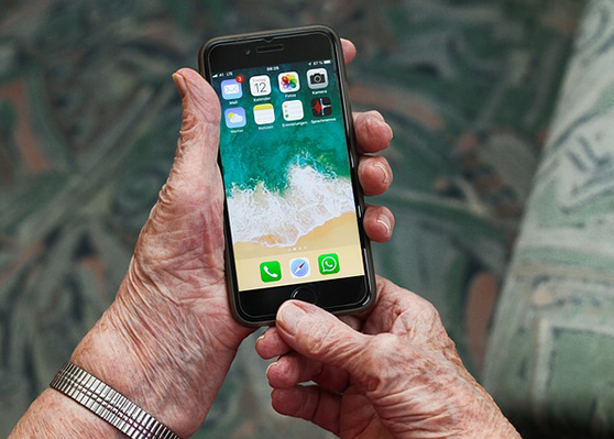 Hände einer älteren Person halten ein Smartphone