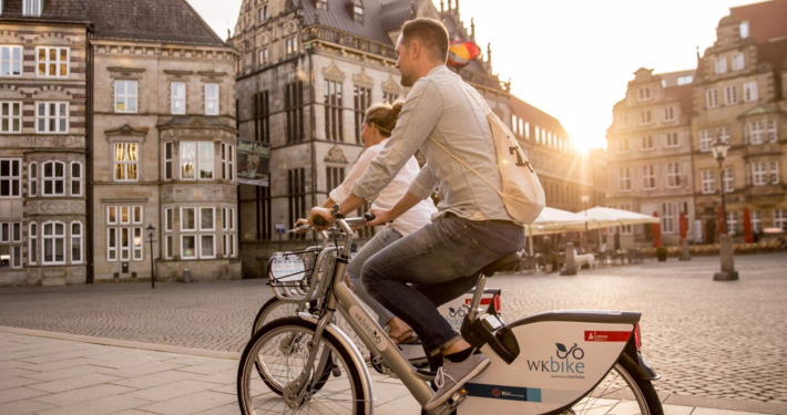 Zwei Menschen fahren auf Fahrrädern über den Marktplatz in Bremen.