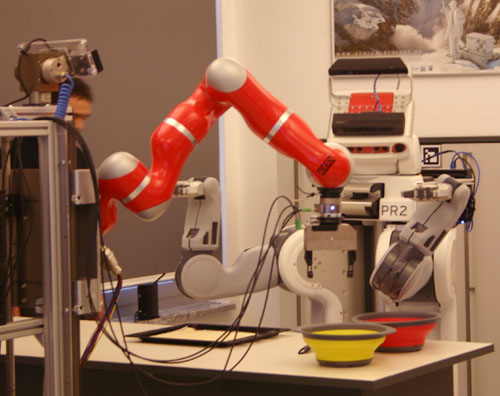 Ein roter Roboterarm neben zwei farbigen Schalen.