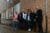 Eine Gruppe aus Männern und Frauen posiert für ein Foto vor einer Backsteinmauer.