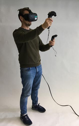 Ein Mann trägt eine VR-Brille und verwendet Handhelds.