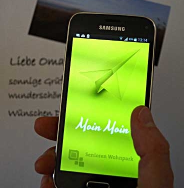 Eine Hand hält ein Smartphone, darauf ist die Moin Moun App zu sehen.