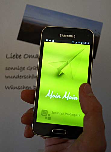 Eine Hand hält ein Smartphone, darauf ist die Moin Moun App zu sehen.