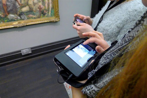 Zwei Personen stehen mit Tablets in den Händen vor einem Gemälde in der Kunsthalle Bremen.
