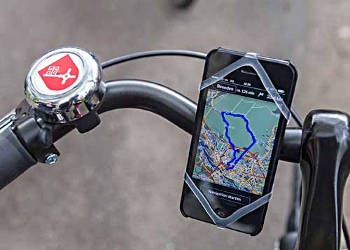 Nahaufnahme von einem Fahrradlenker, an dem ein Smartphone befestigt ist, das einen Stadtplan mit einer markierten Route anzeigt.