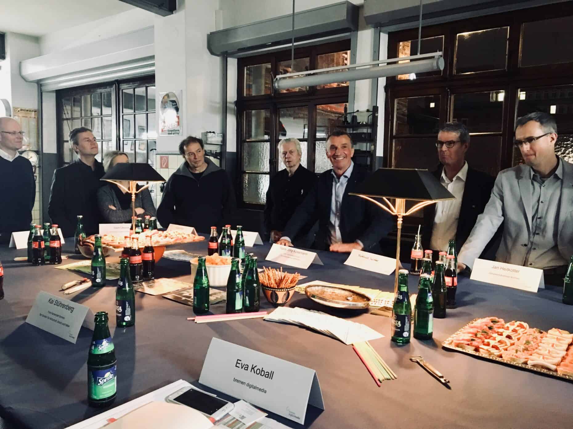 Eine Gruppe Menschen sitzt um einen Tisch herum, auf dem Essen und Getränke stehen.