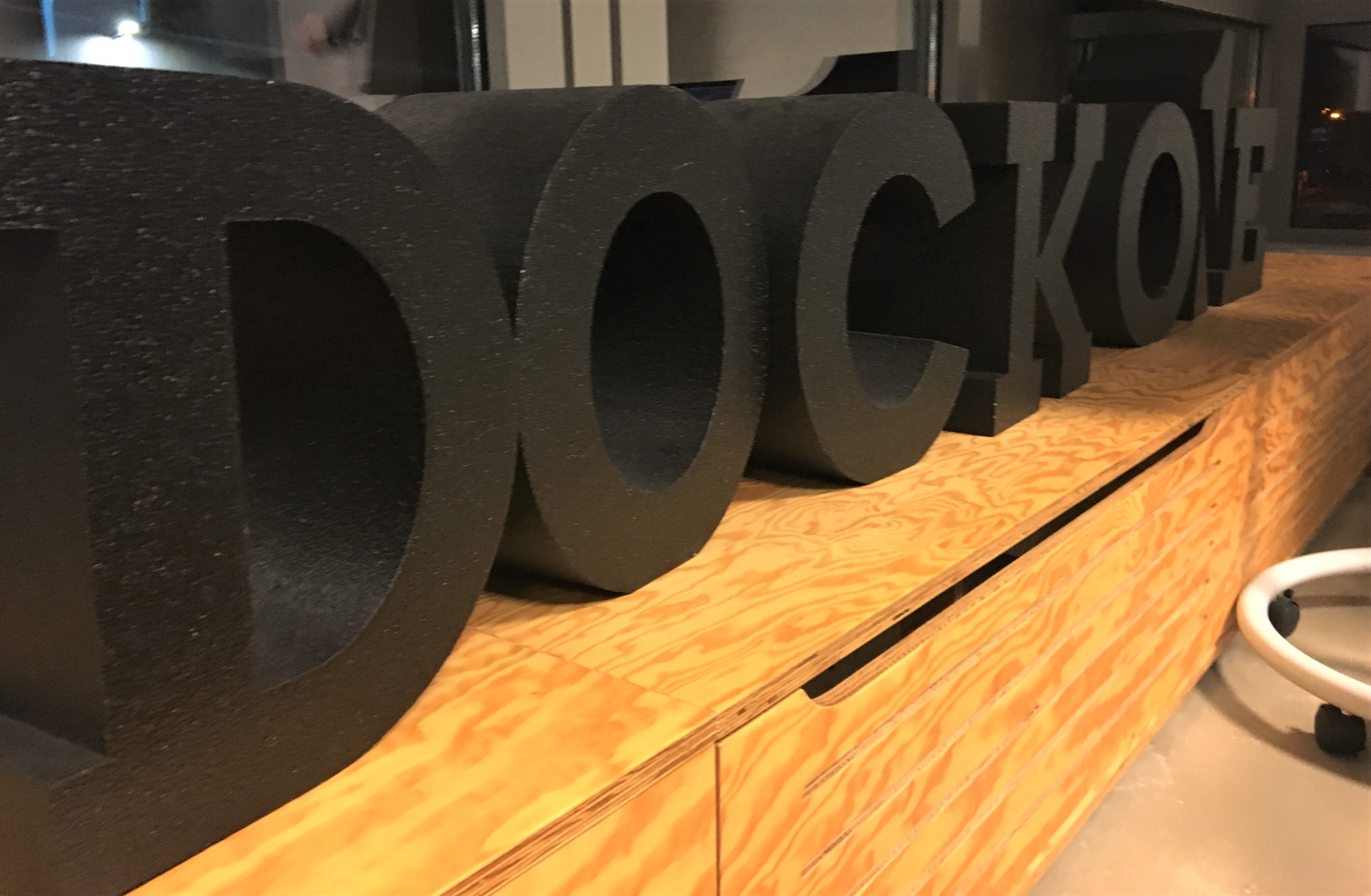 Schwarze Dock One Buchstaben stehen auf einer Holzempore