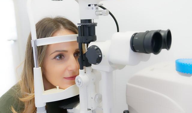 Eine Frau sitzt an einem Gerät, dass zur Augenuntersuchung genutzt wird.