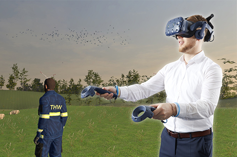 Ein Mann mit einer VR-Brille und Handhelds, im Hintergrund ist ein Screenshot eines Spiels