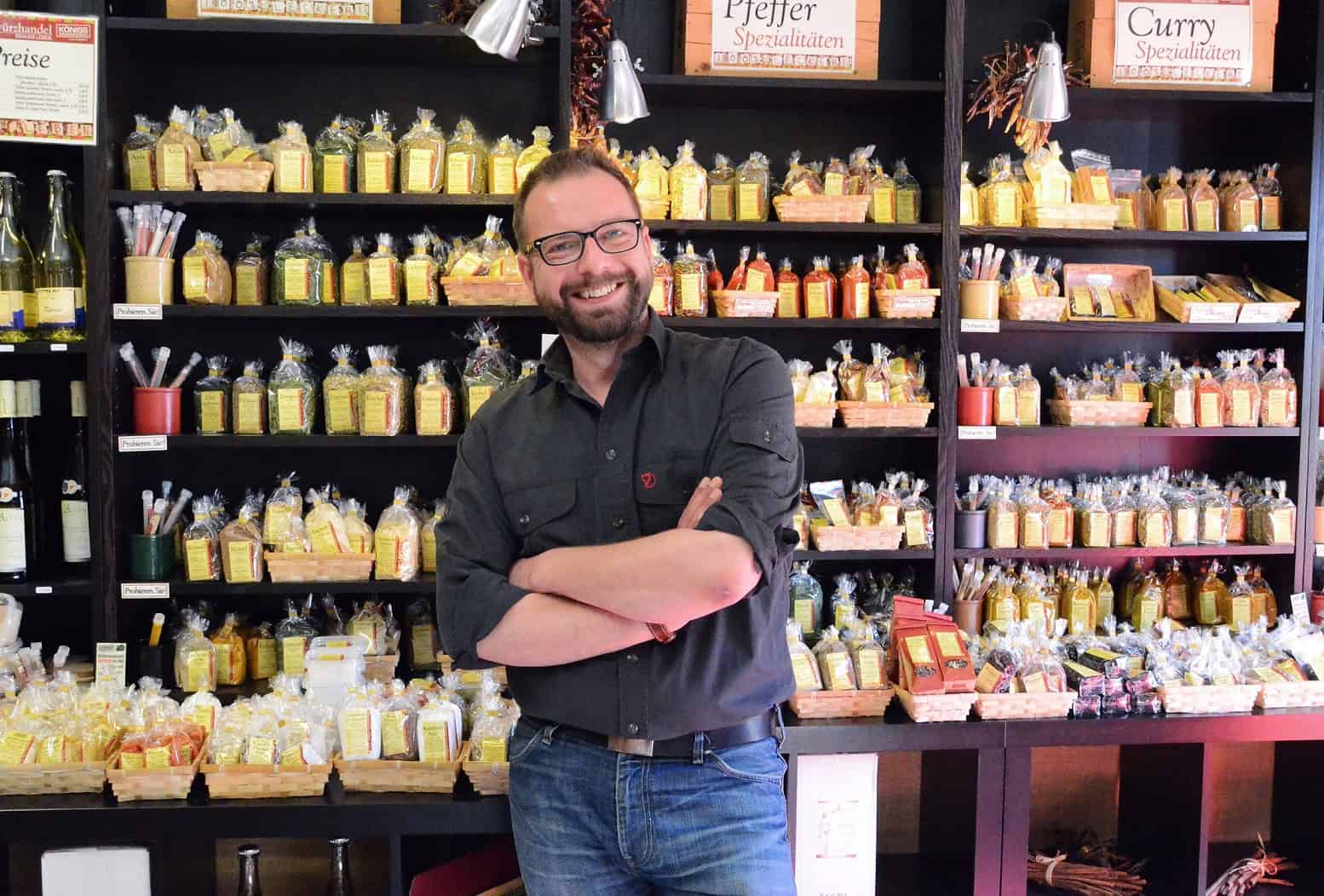 Daniel König, Gründer und Geschäftsführer der Bremer Gewürzhandel GmbH, steht in seinem LAden vor dem Gewürzregal.