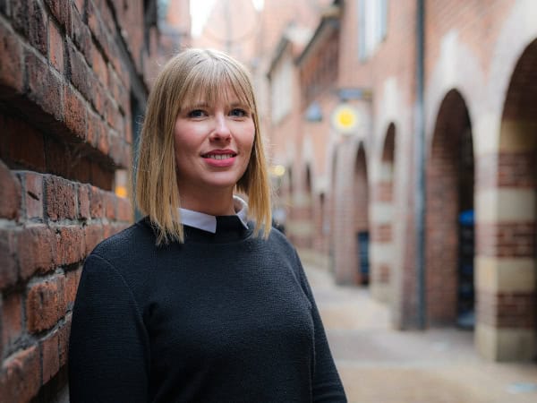 Portraitfoto von Laura Heissenbüttel vor einer Backsteinmauer