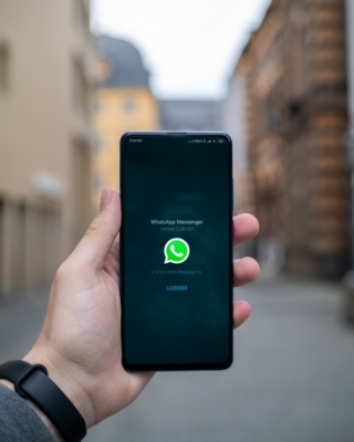 Hand hält ein Handy mit dem Whatsapp Logo auf dem Bildschirm