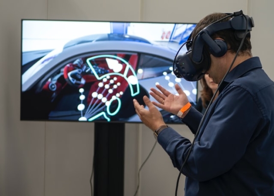 Ein Mann trägt eine VR-Brille und steht vor einem Bildschirm