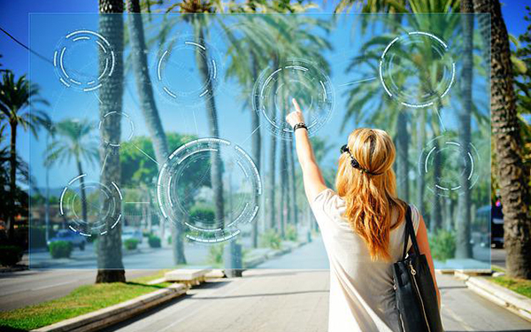 Eine Frau steht mit dem Rücken zum Bild vor einer von Palem gesäumten Straße und klickt auf virtuelle transparente Kreise, die in der Luft schweben.