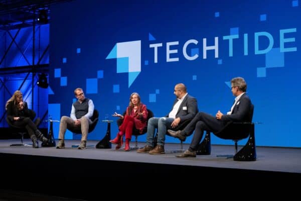 Menschen sitzen auf Stühlen auf der Bühne und unterhalten sich.