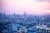 Blick auf die Skyline einer Stadt vor rosa-lilafarbenem Himmel. Darüber liegen Icons von Wolken und dem WLAN-Symbol.