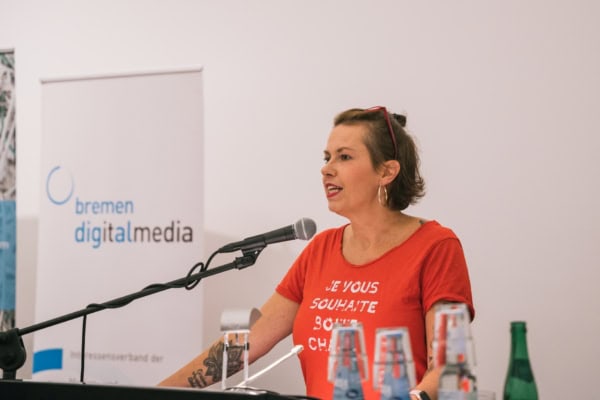 Eine Frau steht am Rednerpult an einem Mikrofon und spricht.