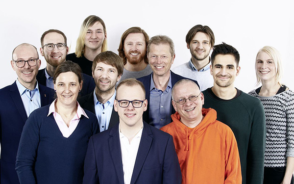 Eine Gruppe von 12 Personen steht für ein Gruppenfoto zusammen und lächelt in die Kamera.