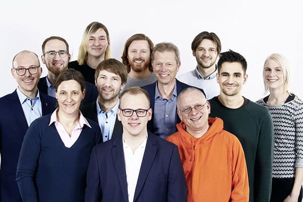 Eine Gruppe von 12 Personen steht für ein Gruppenfoto zusammen und lächelt in die Kamera.