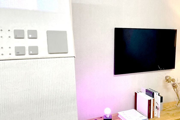 Fotografie einer Zimmerwand, es sind Anschnitte von Möbel, und einem Fernseher erkennbar.