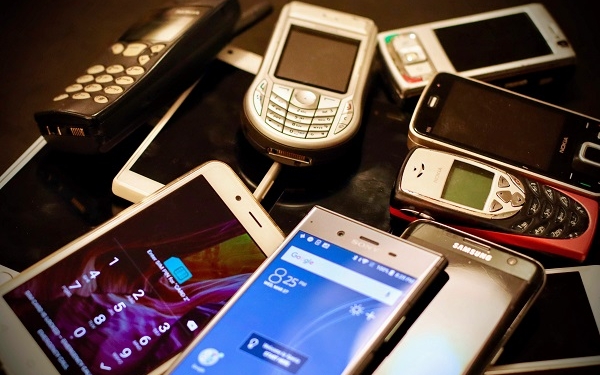 Viele verschiedene Smartphones und Handys liegen auf einem Haufen.