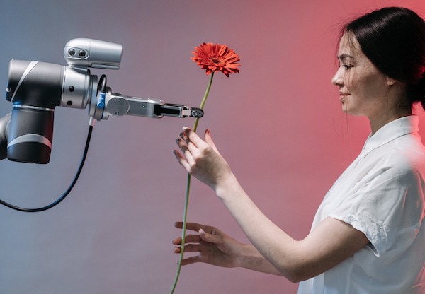 Ein Roboterarm überreicht einer Frau eine rote Blume.