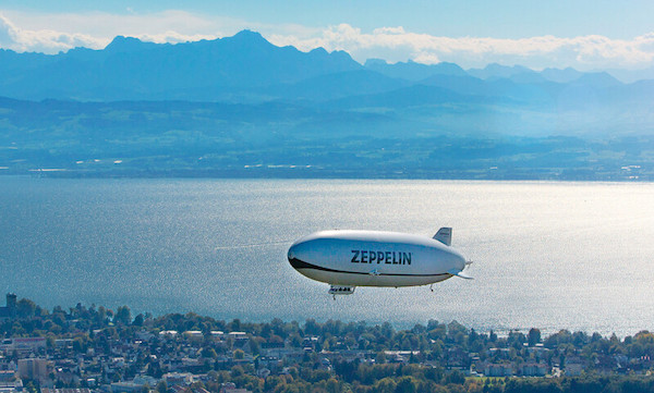 Luftaufnahme eines Zeppelings über einer Stadt und Wasser.