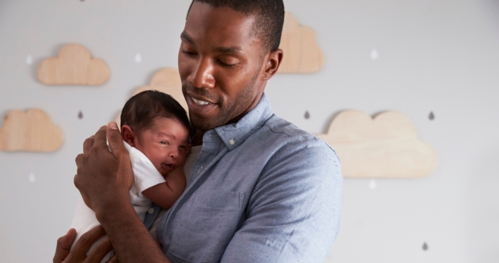 Ein Mann hält ein Neugeborenes auf dem Arm.