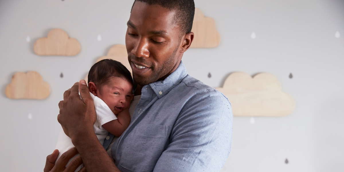 Ein Mann hält ein Neugeborenes auf dem Arm.