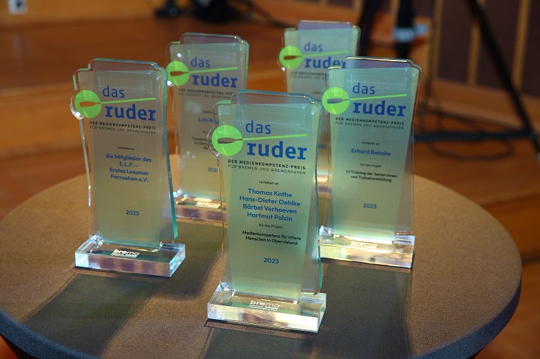 Mehrere identische Awards aus Glas stehen auf einem runden Tisch.