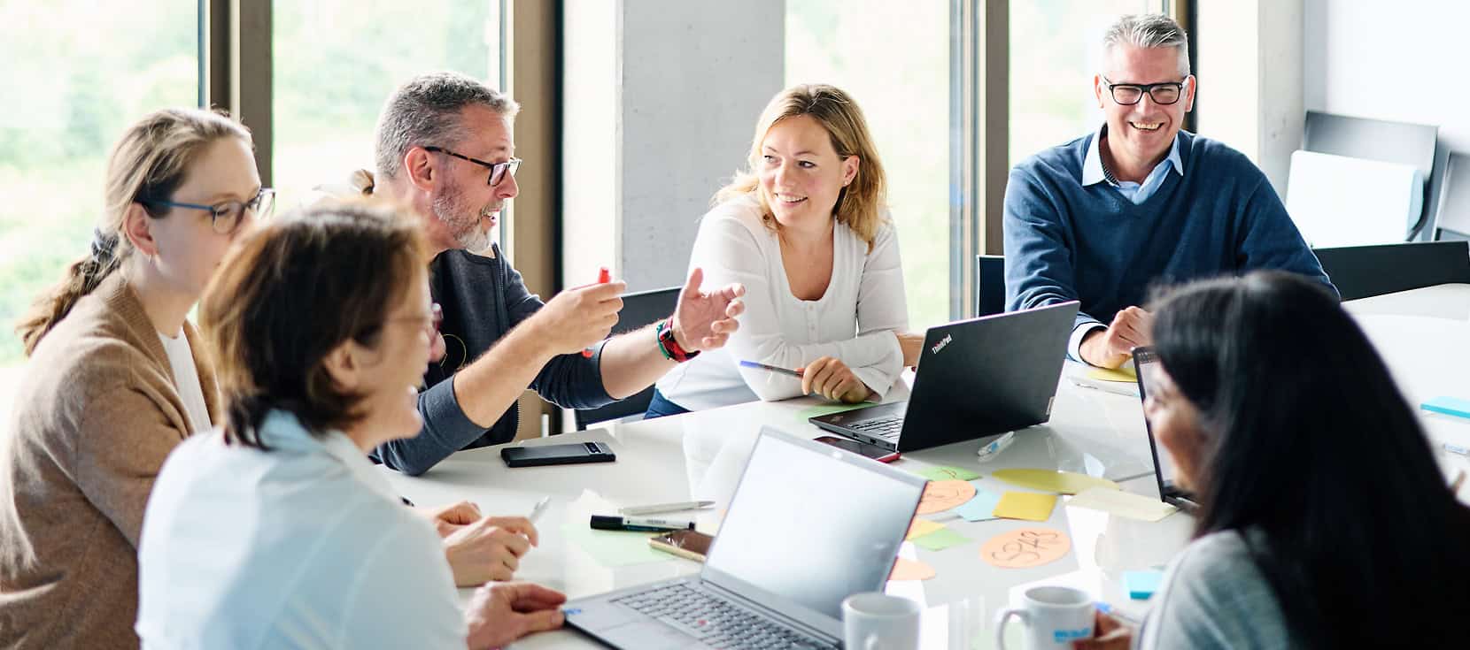 Sechs Personen sitzen an einem Konferenztisch und sprechen miteinander.