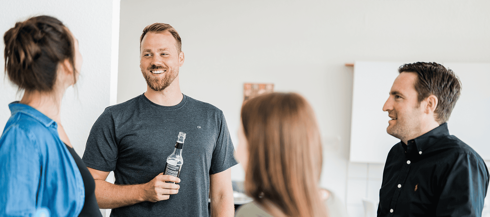 Vier Personen stehen in einer Runde und sprechen miteinander.