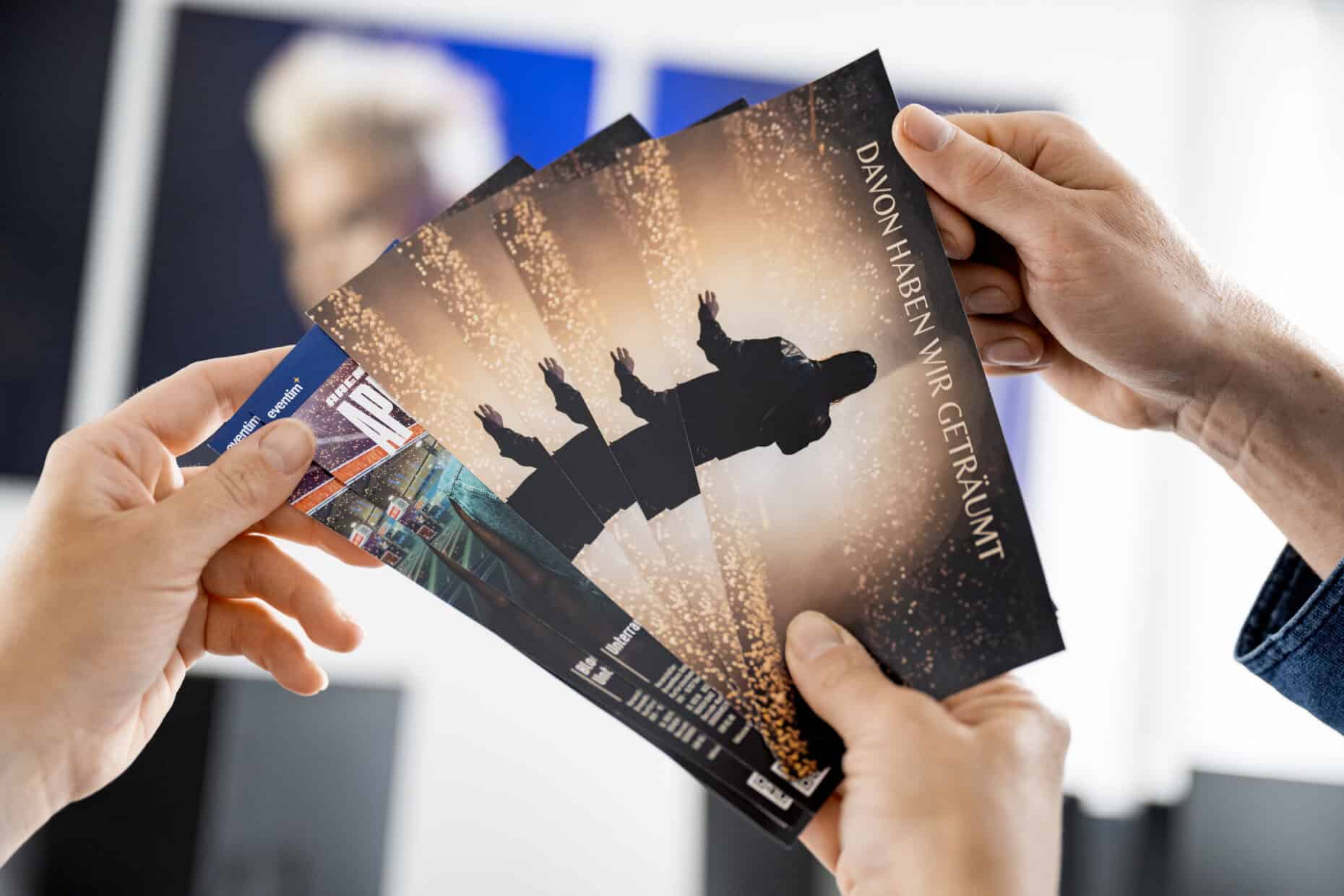 Nahaufnahme von sechs in der Hand aufgefächerten Event-Tickets.