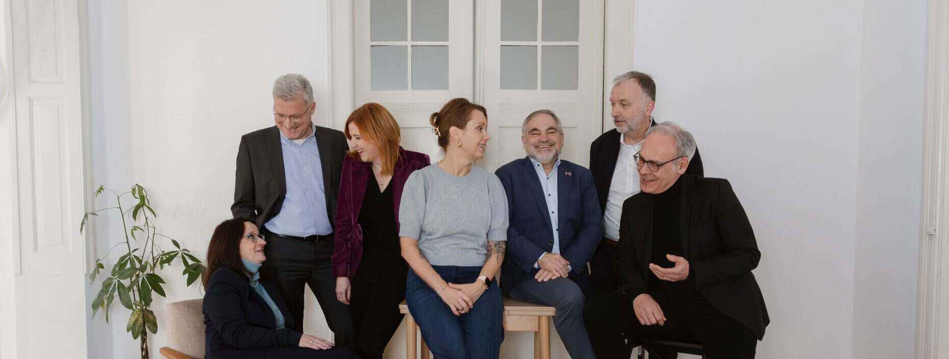 Gruppenfoto von sieben Personen, die sich miteinander unterhalten.