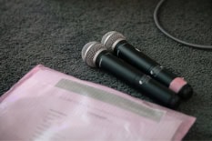 Zwei Mikrofone liegen auf dem Boden mit einer Mappe.