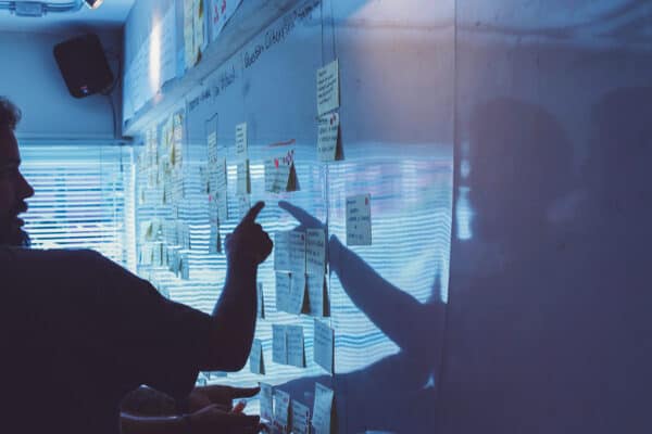 Eine Person zeigt auf Post-Its an einer Wand.