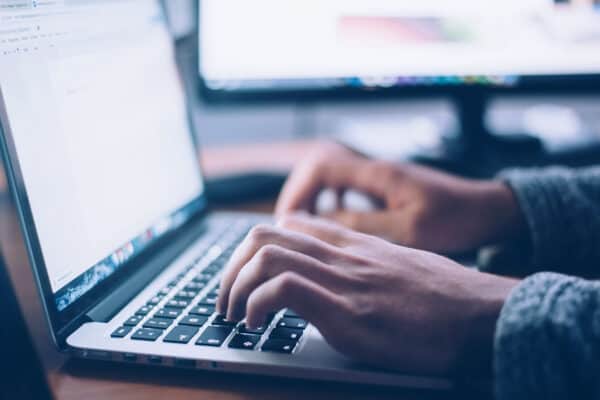 Zwei Hände tippen auf einer Laptoptastatur.