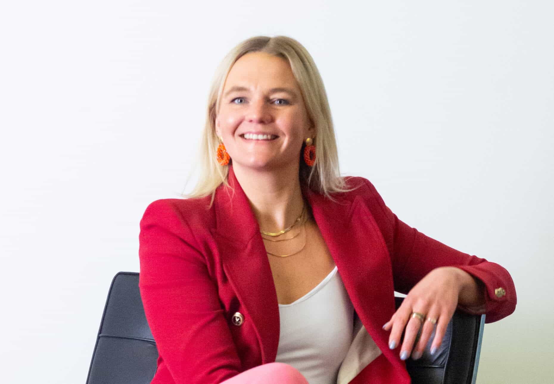 Porträt einer Frau, die auf einem Stuhl sitzt und in die Kamera lächelt.