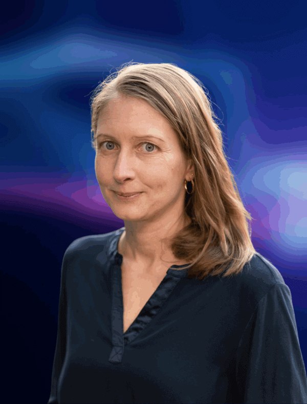 Portrait einer Person, die freundlich in die Kamera guckt. Der dunkelblau-liafarben und verschwommene Hintergrund ist in der Bildberarbeitung nachträglich hinzugefügt worden.