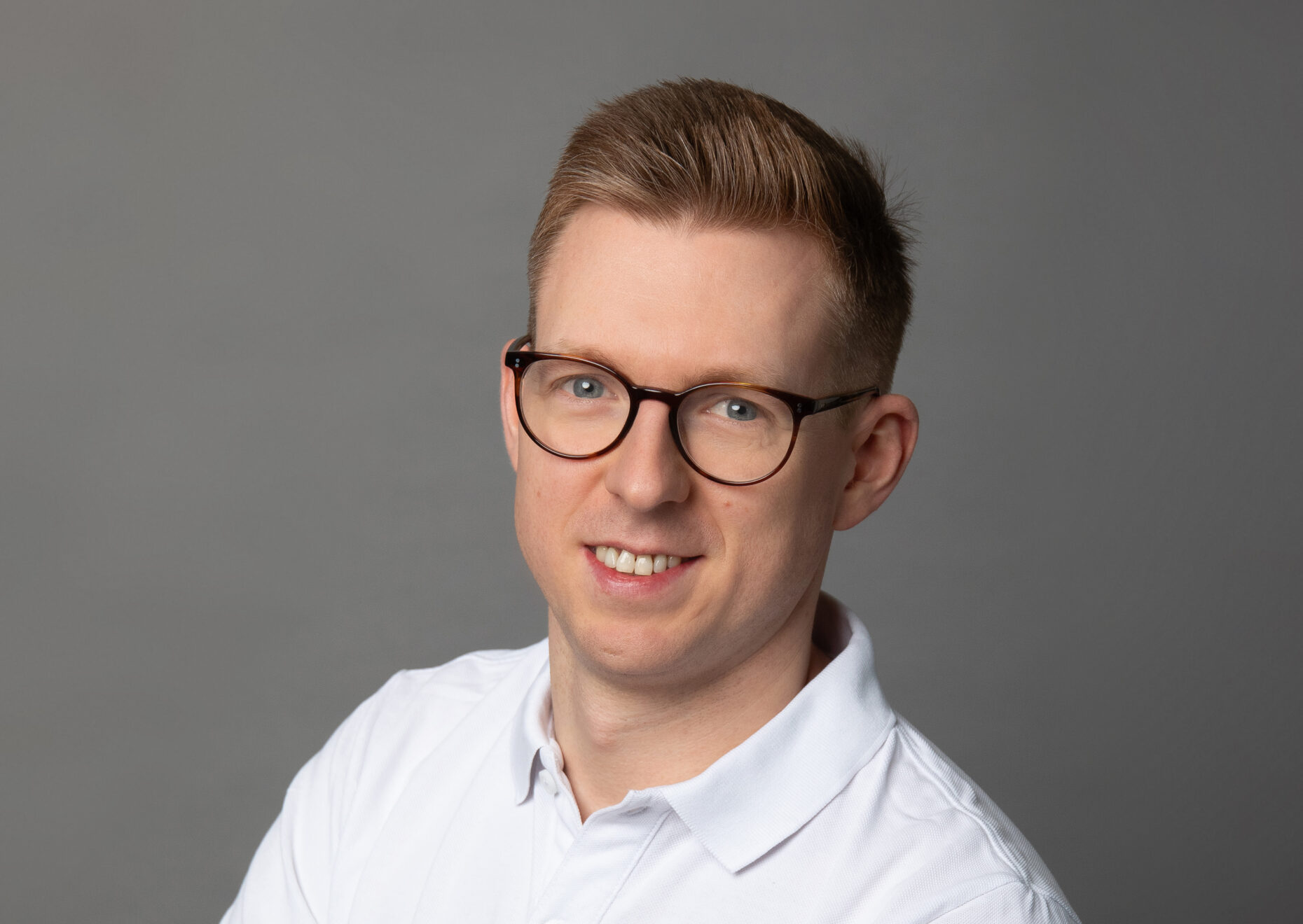 Portraitaufnahme eines Mannes, der in die Kamera lächelt.