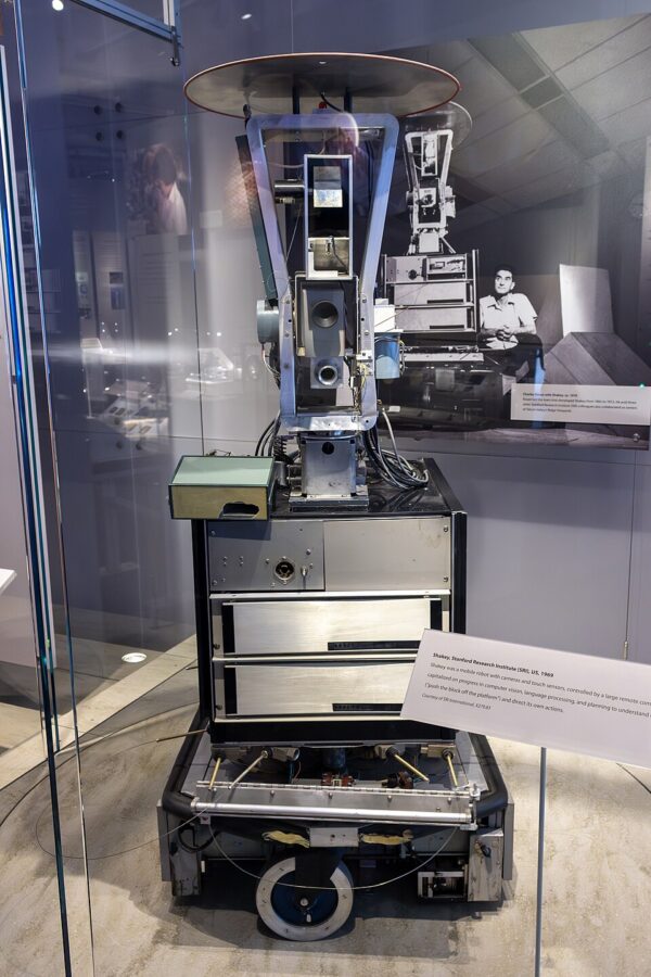 Ein silberner Roboter in einem Glaskasten.