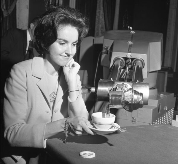 Eine Frau kriegt eine Tasse Kaffee eingeschenkt von einem Roboter.